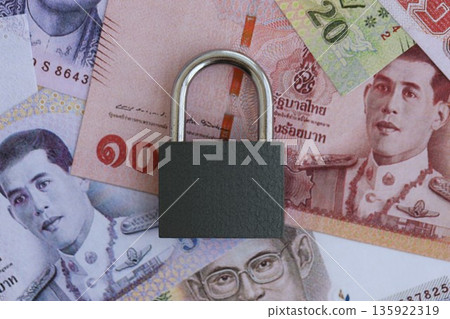 Thai baht currency money bills and padlock close up. The concept of sanctions and financial safety Thai baht currency money bills and padlock close up. The concept of sanctions and financial safety 135922319