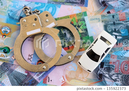 Kuwaiti dinar currency money bills and toy car with handcuffs close up. The concept of car accident 135922373