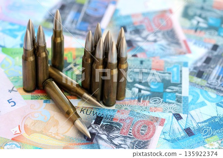 Kuwaiti dinar currency money bills and rifle bullets close up. The concept of warfare and gun selling Kuwaiti dinar currency money bills and rifle bullets close up. The concept of warfare and gun selling 135922374
