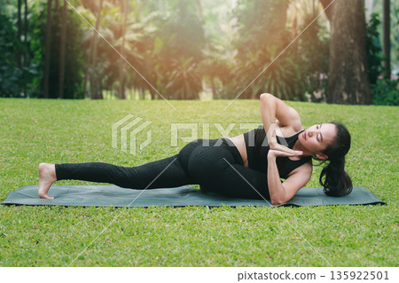 Asian woman practicing yoga in Prep Poses for Side Crane Pose for Parsva Bakasana on the mat in outdoor park. 135922501
