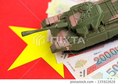 Vietnamese dong currency money bills and toy tank on flag close up. The concept of army funds and weapons sales 135922628
