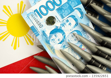 Philippines peso currency money bills and rifle bullets on flag close up. The concept of warfare and gun selling Philippines peso currency money bills and rifle bullets on flag close up. The concept of warfare and gun selling 135922651