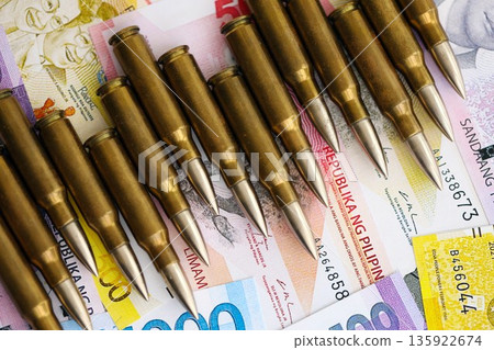 Philippines peso currency money bills and rifle bullets close up. The concept of warfare and gun selling Philippines peso currency money bills and rifle bullets close up. The concept of warfare and gun selling 135922674