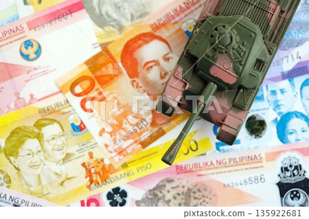 Philippines peso currency money bills and toy tank close up. The concept of army funds and weapons sales Philippines peso currency money bills and toy tank close up. The concept of army funds and weapons sales 135922681