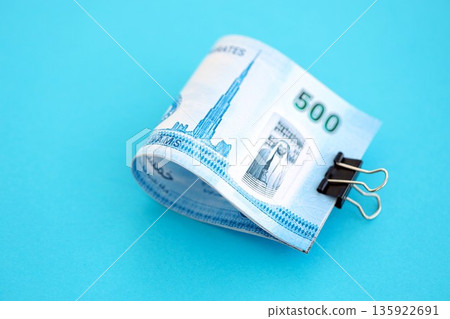 United Arab Emirates dirham money bills in big amount on blue close up. Finance and banking concept United Arab Emirates dirham money bills in big amount on blue close up. Finance and banking concept 135922691