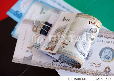 United Arab Emirates dirham currency money bills lies on flag close up. The concept of business and investment United Arab Emirates dirham currency money bills lies on flag close up. The concept of business and investment 135922692