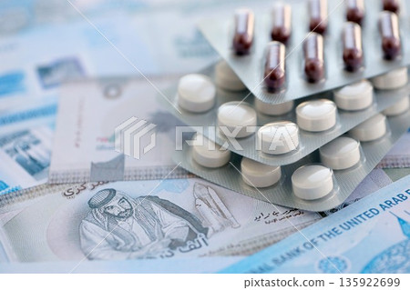 United Arab Emirates dirham currency money bills and medicine pills close up. The concept of medicine and pharmacy United Arab Emirates dirham currency money bills and medicine pills close up. The concept of medicine and pharmacy 135922699