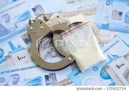 United Arab Emirates dirham currency money bills and cocaine pack with handcuffs close up. The concept of drug crimes 135922714