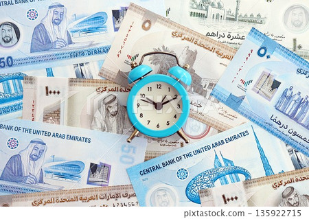 United Arab Emirates dirham currency money bills and alarm clock close up. The concept of time management and income 135922715