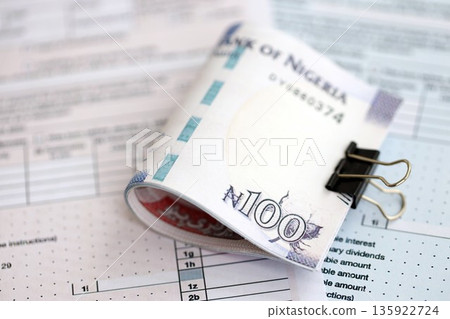 Nigerian naira money bills on tax form close up. Taxation and accounting concept Nigerian naira money bills on tax form close up. Taxation and accounting concept 135922724