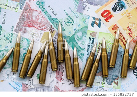 Nigerian naira currency money bills and rifle bullets close up. The concept of warfare and gun selling 135922737
