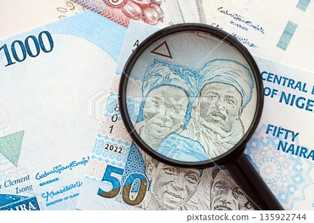 Nigerian naira currency money bills and magnifying glass close up. The concept of financial monitoring and taxation Nigerian naira currency money bills and magnifying glass close up. The concept of financial monitoring and taxation 135922744