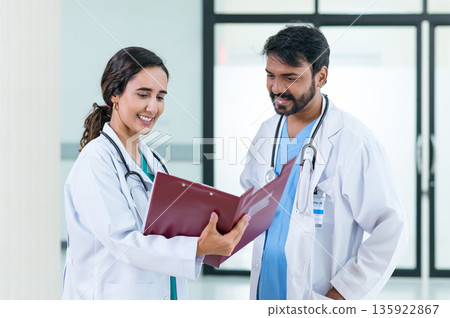 male and female doctors in white medical uniforms discuss patient anamnesis together. team brainstorming make decision concept. male and female doctors in white medical uniforms discuss patient anamnesis together. team brainstorming make decision concept. 135922867