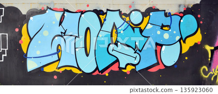 The old wall decorated with paint stains in the style of street art culture. Colorful background of full graffiti painting artwork with bright aerosol outlines on wall. Colored background texture The old wall decorated with paint stains in the style of street art culture. Colorful background of full graffiti painting artwork with bright aerosol outlines on wall. Colored background texture 135923060