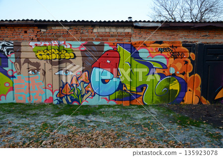 The old wall decorated with paint stains in the style of street art culture. Colorful background of full graffiti painting artwork with bright aerosol outlines on wall. Colored background texture 135923078
