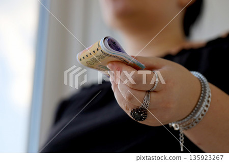 Woman hand with indian rupees bills close up. Concept of financial operations in cash in India Woman hand with indian rupees bills close up. Concept of financial operations in cash in India 135923267