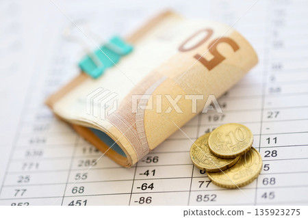 Heap of euro money bills in stationery clip on papers with calculations and receipts close up. Business and accounting concept Heap of euro money bills in stationery clip on papers with calculations and receipts close up. Business and accounting concept 135923275