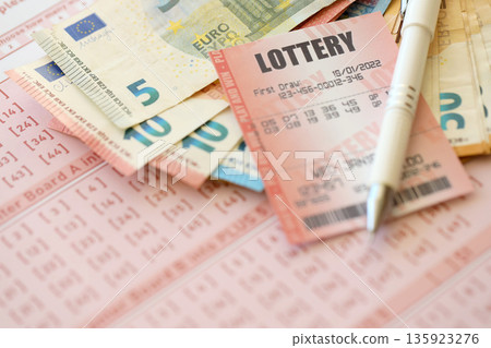 Lottery ticket and gambling receipt on table with pen and European Union euro money bills close up Lottery ticket and gambling receipt on table with pen and European Union euro money bills close up 135923276