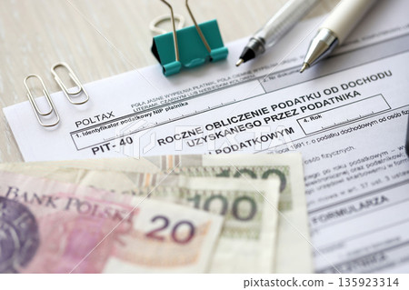 Annual calculation of tax on income obtained by taxpayer, PIT-40 tax forms on accountant table with pen and polish zloty money bills close up 135923314