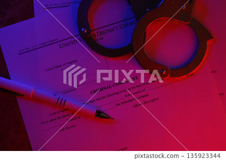 District Court Criminal complaint court papers with handcuffs and blue pen on table close up 135923344