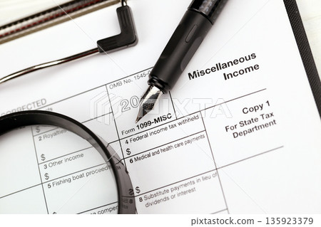 IRS Form 1099-misc Miscellaneous income blank on A4 tablet lies on office table with pen and magnifying glass close up 135923379