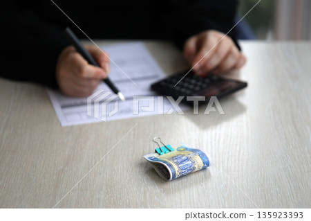 Accountant start to fill Iranian tax form on office table. Taxation period and annual taxpayers routine in Iran Accountant start to fill Iranian tax form on office table. Taxation period and annual taxpayers routine in Iran 135923393