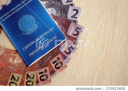 Brazilian work card and social security blue book and reais money bills close up Brazilian work card and social security blue book and reais money bills close up 135923408