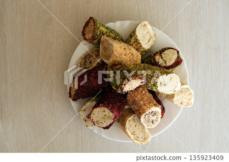 Many rolls of turkish delight with different flavors and fillings in white plate on table. Cuts of Turk Lokumu sweets Many rolls of turkish delight with different flavors and fillings in white plate on table. Cuts of Turk Lokumu sweets 135923409