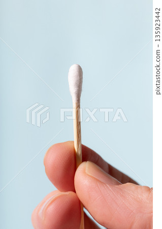 Hand holding cotton swab for ear cleaning and hygiene 135923442