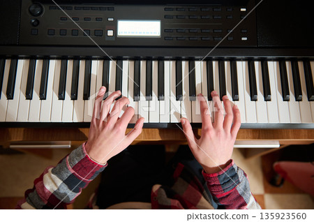 Young Pianist Playing Keyboard At Home In Plaid Shirt, Focused On Notes And Rhythm 135923560