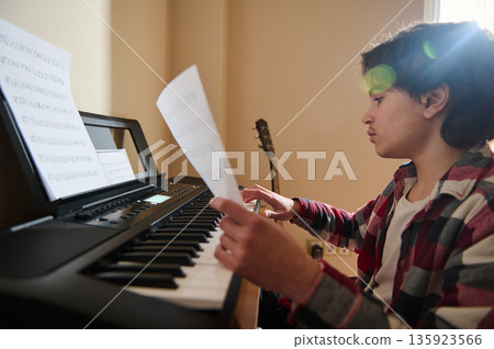Teenage Boy Playing Keyboard With Sheet Music In A Cozy Music Room 135923566