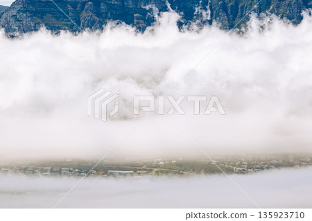 Aerial view of foggy Cape Town with mountain range on top. Low clouds covering residential area. South Africa travel and vacation. 135923710