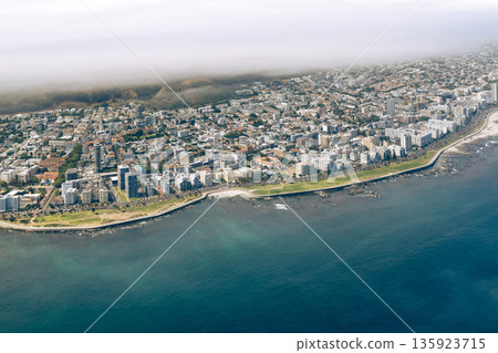 Aerial view of Cape Town coastal city at ocean with mountain shrouded in clouds. Urban landscape from above, luxury vacation concept. 135923715
