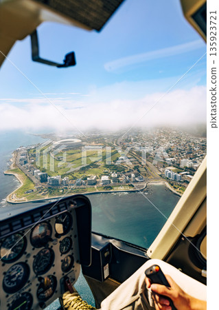 Man flying helicopter over Cape Town, South Africa, offering a luxury vacation and tour experience with aerial view of the city Man flying helicopter over Cape Town, South Africa, offering a luxury vacation and tour experience with aerial view of the city 135923721