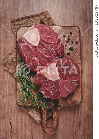 knuckle on the bone, raw meat for ossobuco, on a wooden chopping board, with a sprig of rosemary, and spices, top view, no people, knuckle on the bone, raw meat for ossobuco, on a wooden chopping board, with a sprig of rosemary, and spices, top view, no people, 135923787