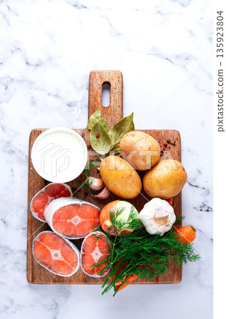 Fresh ingredients arranged on a wooden cutting board for cooking a meal in a bright kitchen setting 135923804