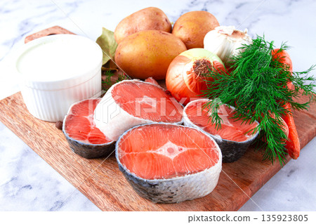 Fresh ingredients arranged on a wooden cutting board for cooking a meal in a bright kitchen setting 135923805