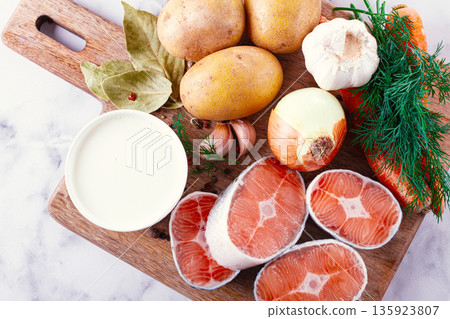 Fresh ingredients arranged on a wooden cutting board for cooking a meal in a bright kitchen setting Fresh ingredients arranged on a wooden cutting board for cooking a meal in a bright kitchen setting 135923807