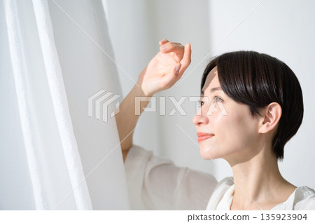 A woman with short hair basking in the sunlight on a white background 135923904