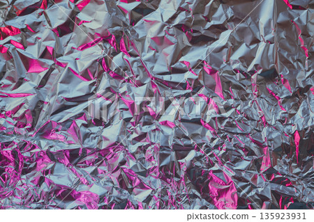Silver aluminum foil showing creased texture with bright pink reflections Silver aluminum foil showing creased texture with bright pink reflections 135923931