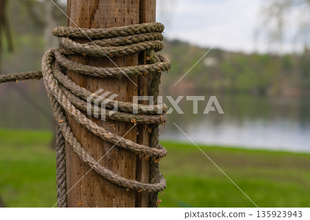 Closeup of weathered rope wrapped around wooden post by lake in Nova Zivohost, Czech Republic 135923943