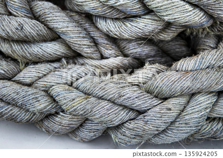 Macro close up of thick braided gray rope showing twisted fibers and detailed texture. 135924205
