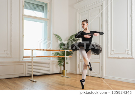 Young ballerina in tutu skirt dancing practicing ballet positions in dance class. Young classical dancer woman in dance studio. Ballet class training. Performer girl rehearsing dance in ballet school Young ballerina in tutu skirt dancing practicing ballet positions in dance class. Young classical dancer woman in dance studio. Ballet class training. Performer girl rehearsing dance in ballet school 135924345