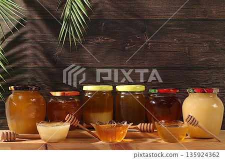 Assortment of meadow, lime, flower, bee honey and nectar for banner at honey fair or sale,Variety of honey varieties in jars and cups on the kitchen table.natural healthy product for health Assortment of meadow, lime, flower, bee honey and nectar for banner at honey fair or sale,Variety of honey varieties in jars and cups on the kitchen table.natural healthy product for health 135924362