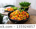 Fresh colorful corn salad with cherry tomatoes, bell pepper, green onions and herbs served in a black bowl on a rustic table. Healthy vegan summer side dish with vibrant vegetables and natural light. 135924857