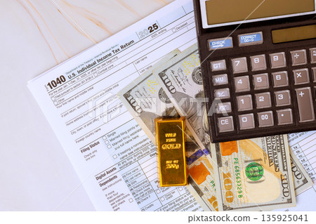 1040 tax return form is placed on accounting table with USA dollar cash, calculator, gold bar ready for financial tax season calculations. 135925041
