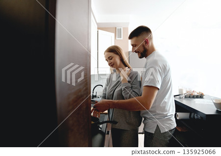 People cooking together in a modern kitchen during morning hours, showing teamwork and shared enjoyment in the culinary process People cooking together in a modern kitchen during morning hours, showing teamwork and shared enjoyment in the culinary process 135925066