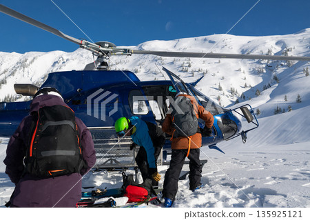 Offpiste heliski trip: elderly friends prepare for powder run with female helicopter pilot in fresh snow Offpiste heliski trip: elderly friends prepare for powder run with female helicopter pilot in fresh snow 135925121
