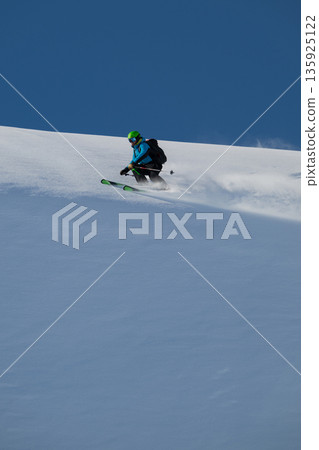 Skier carving fresh powder on a mountain slope under a blue sky, a thrilling winter adventure Skier carving fresh powder on a mountain slope under a blue sky, a thrilling winter adventure 135925122