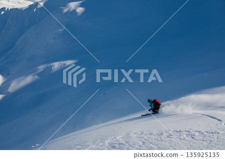 Skier carves through fresh powder on a blue mountain slope in pristine winter conditions 135925135